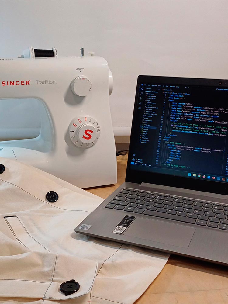 A sewing machine next to a laptop displaying code for a web application, combining traditional sewing tools with modern digital technology.